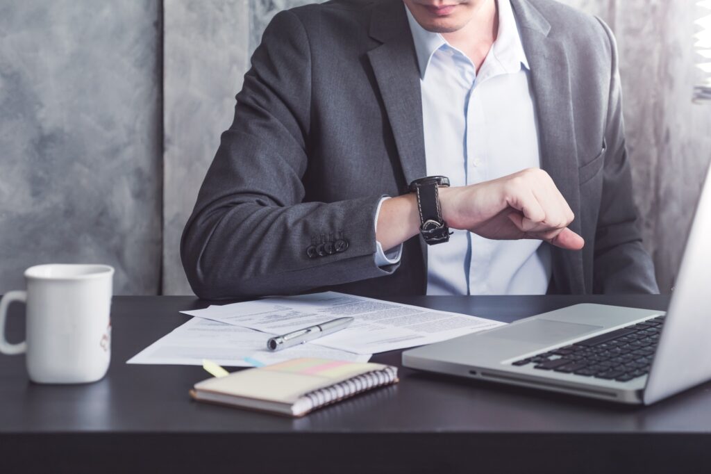 Close up of Businessman working on the desk and checking time on his wrist watch.