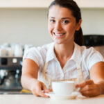 Restaurant employee smiling serving coffee.