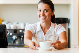 Restaurant employee smiling serving coffee.