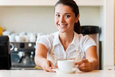 Restaurant employee smiling serving coffee.