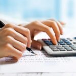 Person using a calculator to calculate taxes