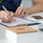 Person filling out paperwork on a clip board