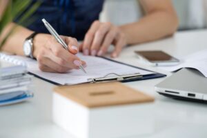 Person filling out paperwork on a clip board
