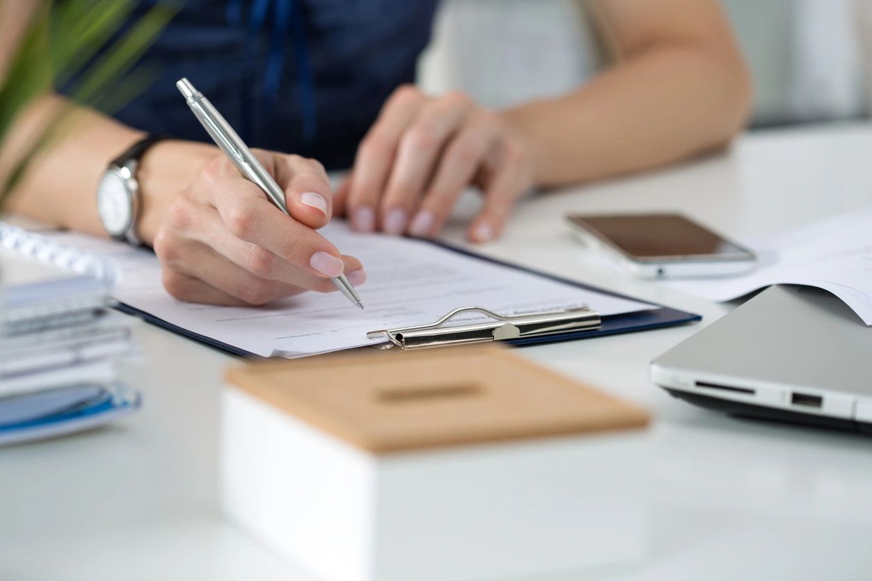 Person filling out paperwork on a clip board